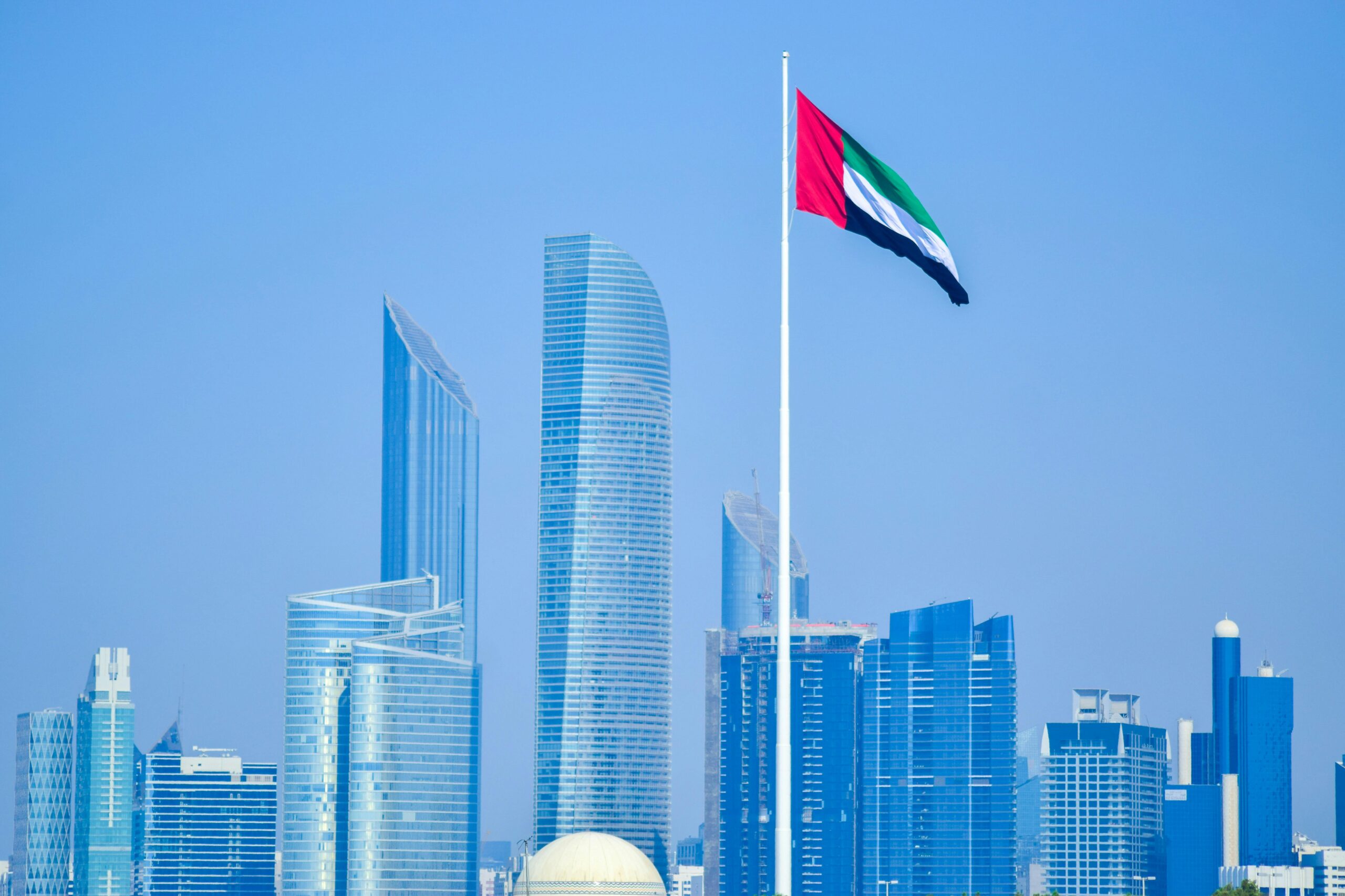Trusted Document Services in UAE Modern skyline of UAE cityscape with national flag waving against clear sky.