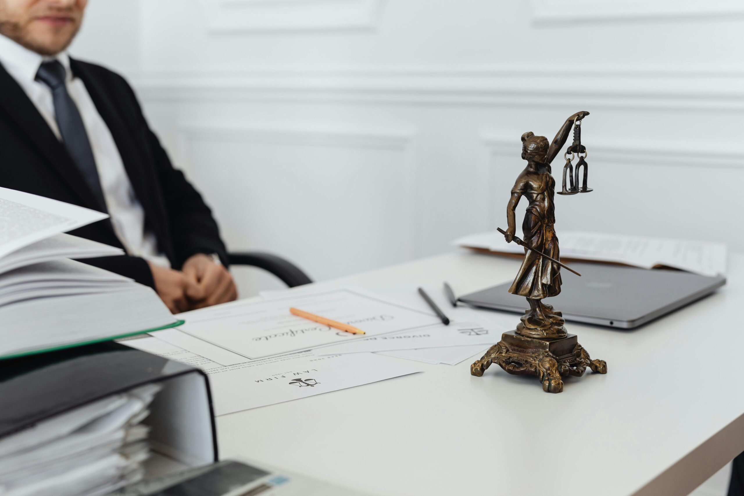 Trusted Document Services in UAE A legal professional's workspace featuring Lady Justice statue, documents, and a laptop.